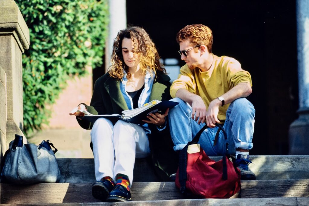 two students chat while studying on outdoor steps on campus in spring 1992