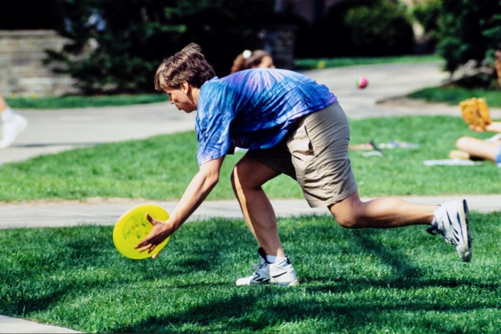 a student catches a Frisbee while playing on a quad in spring 1992