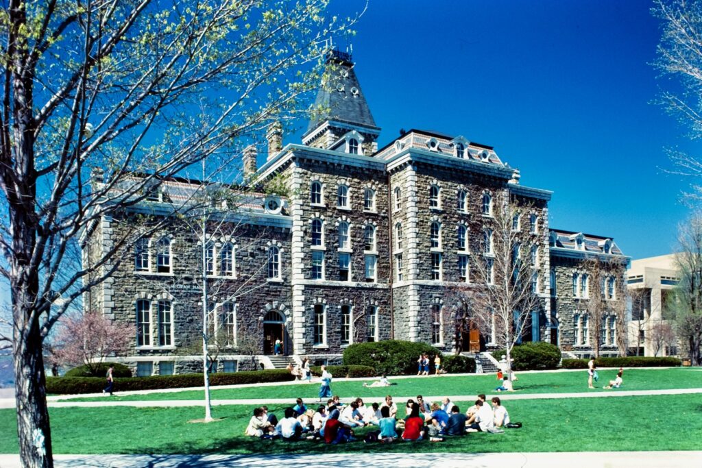 students hold class outdoors, sitting in a circle, on the Arts Quad with McGraw Hall in the background in spring 1987