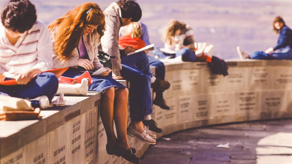 Students sit outside studying on the ledge next to Uris Library overlooking the Slope in the 1970s
