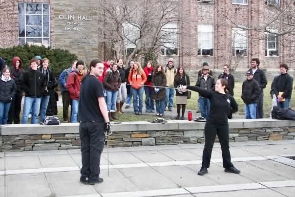 Jennifer Wholey Lehman points her sword at another student during a performance in front of Olin Hall as a group watches.