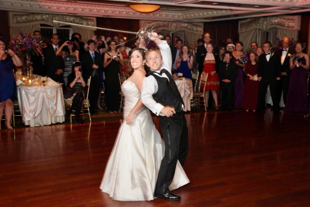 Jennifer Wholey Lehman and Jacob Lehman at their wedding posing back to back with swords during their first fight.
