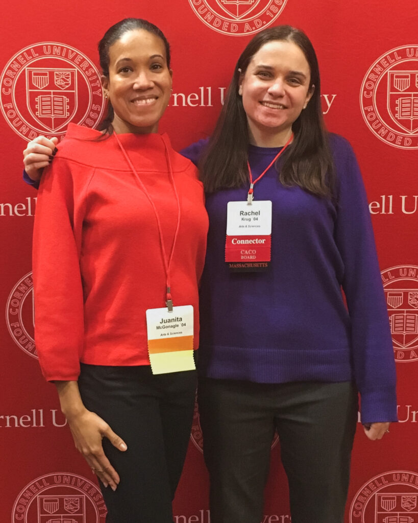 Rachel Krug (right) with a classmate standing in front of a red Cornell University background