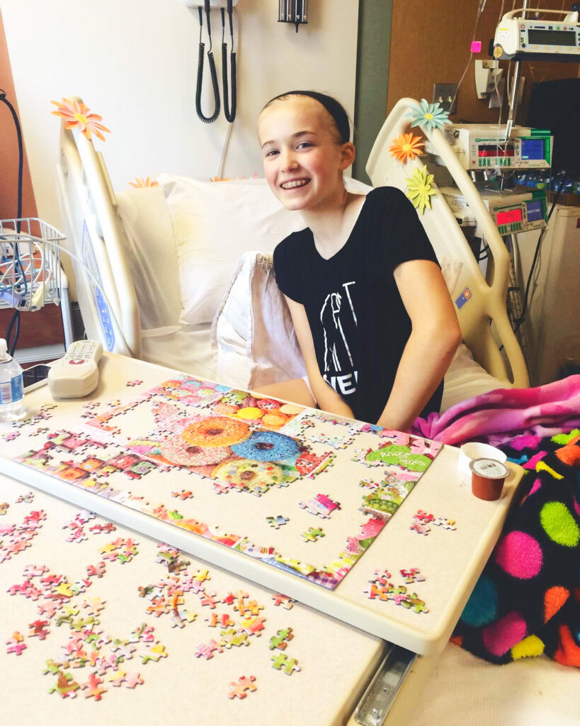 Camille Brady as a tween in a hospital bed doing a jigsaw puzzle