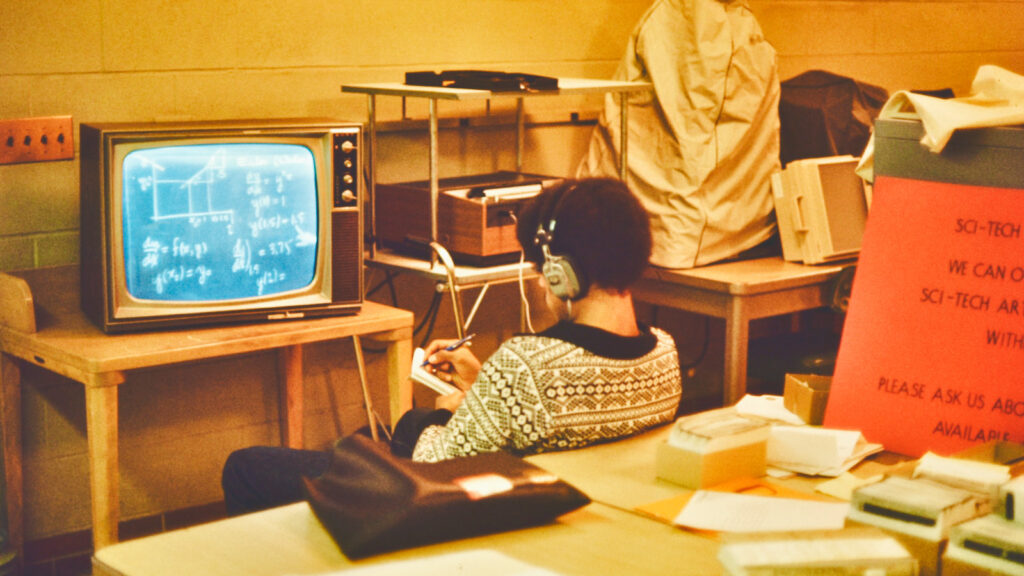 an undated photograph shows a student in Carpenter Library viewing a videotaped "chalkboard lecture" on a TV screen while wearing headphones
