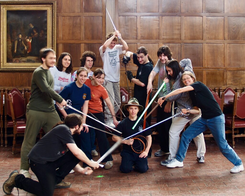 Students in a group point their swords at Jacob Lehman, who is sitting on the floor in front of them.