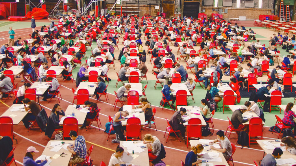 Dozens of tables with students sitting taking exams inside Barton Hall