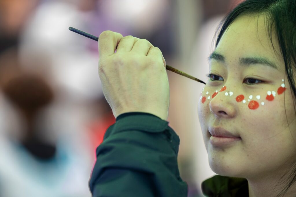 A student gets her face painted with white and red dots