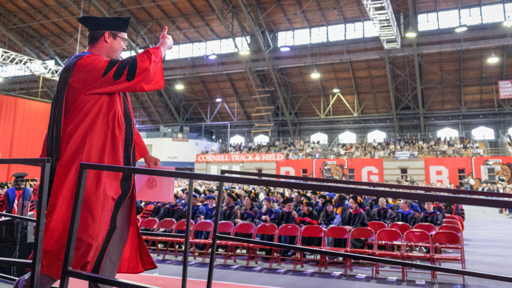 A PhD grad gives a thumbs-up to the Barton crowd