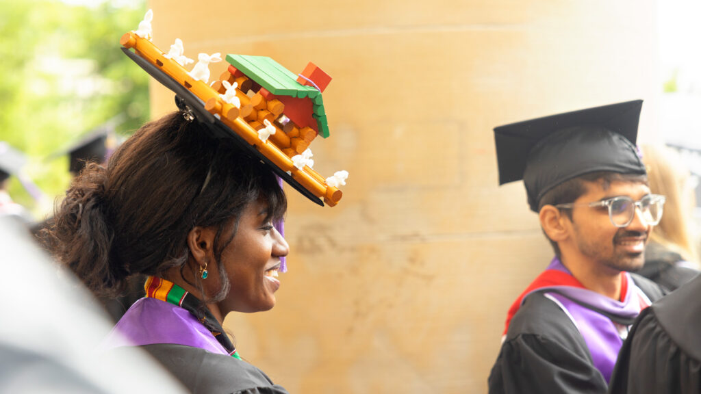 A grad wears a mortarboard decorated with Lincoln Logs in the shape of a cabin