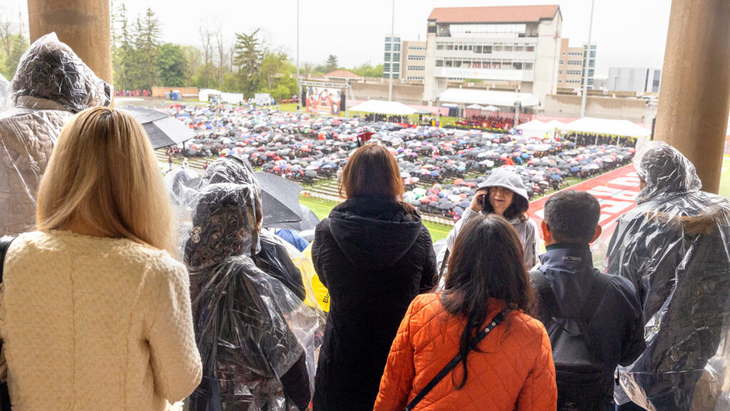 A far-away view of Schoellkopf Field with people under an overhang in the foreground