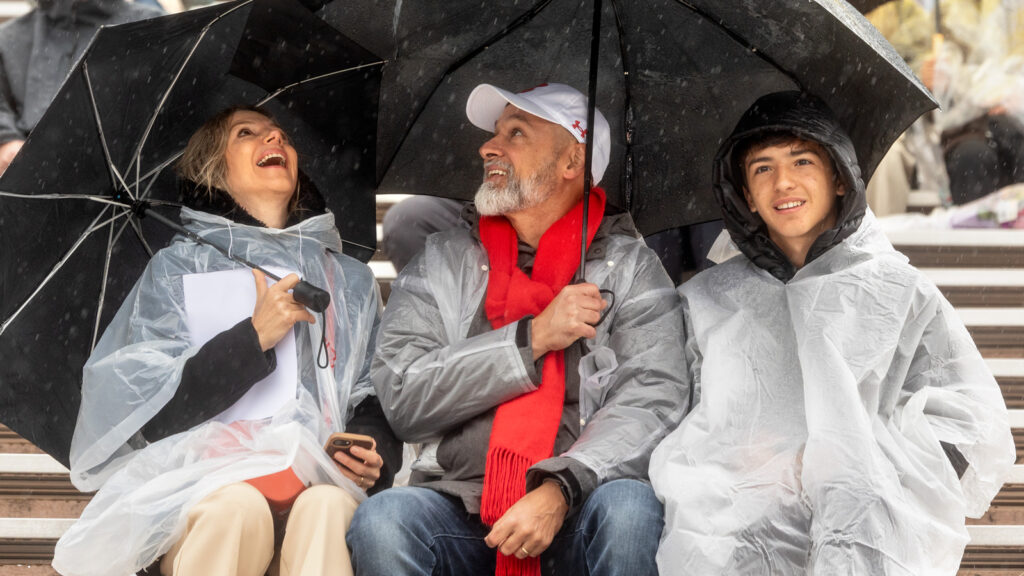 A family in ponchos under umbrellas in the stands