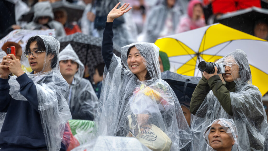 Families wearing clear ponchos wave and take photos