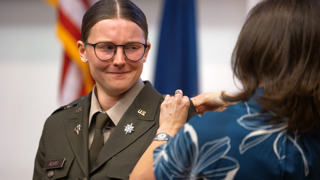 A young woman in an army uniform has her insignia pinned on an epaulet