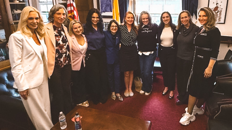 Rachel Foster stands and smiles with a group of members from the Democratic Women's Caucus.