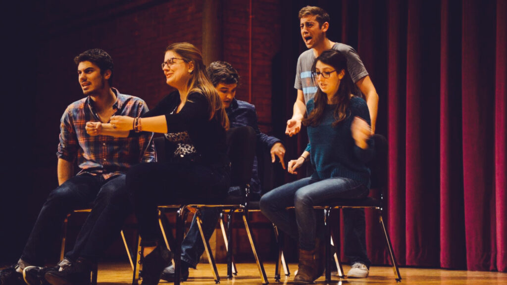 Jake Potashnick and four classmates performing on a stage with red curtain behind them for the Whistling Shrimp.
