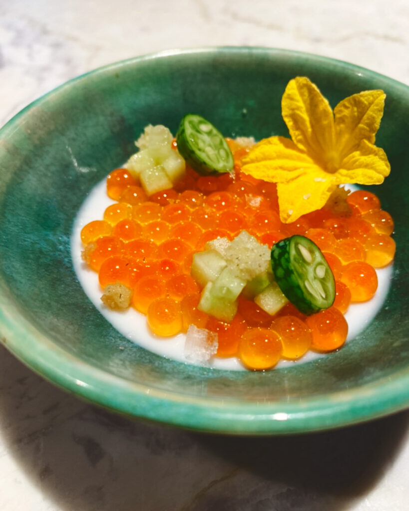 Bright orange ikura with horseradish pan cotta in a green bowl.