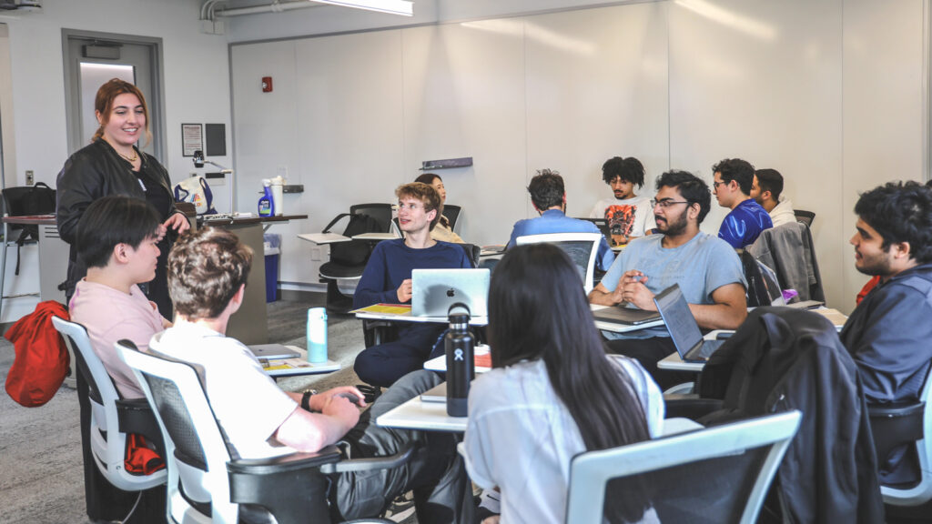 Lara Patz speaking with a group of Cornell students who are sitting around a table