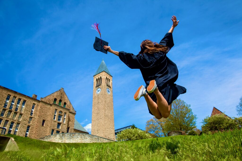 Student jumping near McGraw Clocktower for graduation.
