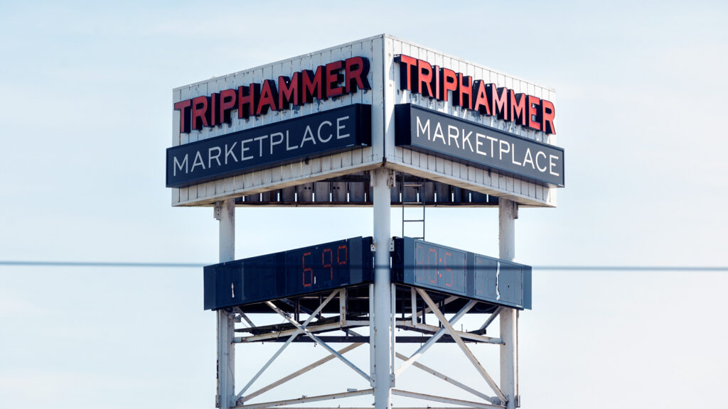 The top of the Triphammer Marketplace sign, including screens that display the temperature and time.