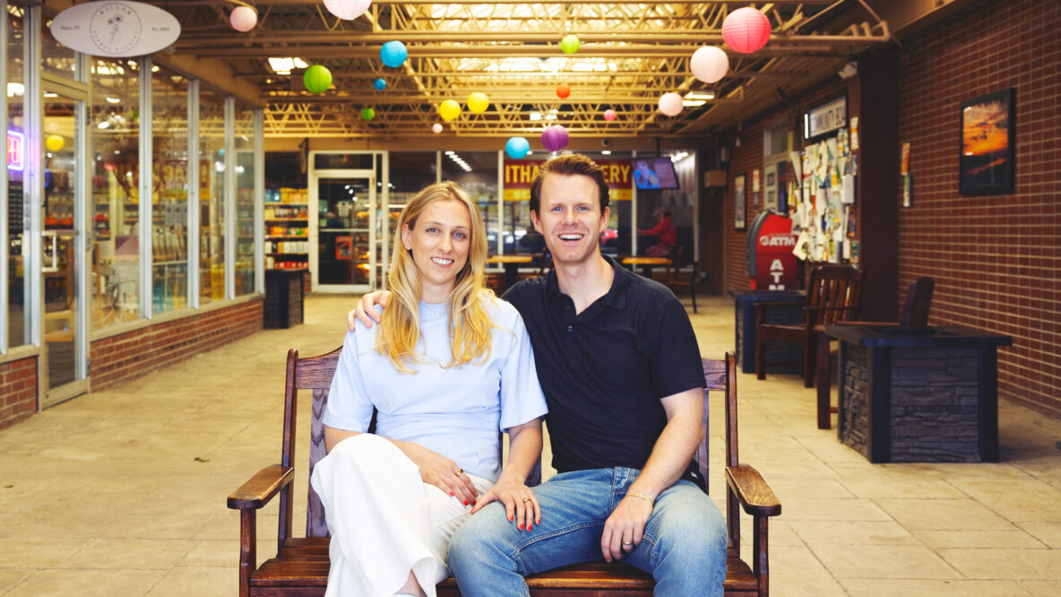 Spencer Kopko and Kristen Ferguson Kopko sitting on a bench together smiling inside the Triphammer Mall.