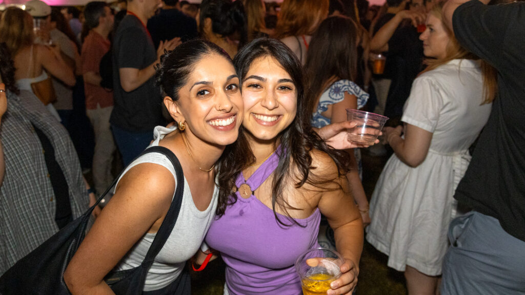 Two alumni smile for a photo together at a tent party during Reunion 2026