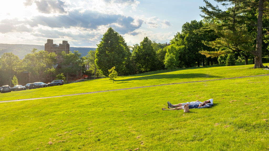 Two alumni lie on the grass together on the Slope during a quiet moment during Reunion 2026