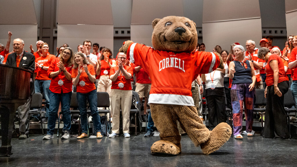 Touchdown strikes a pose on stage during Reunion 2026’s Cornelliana Night as alumni clap behind him.