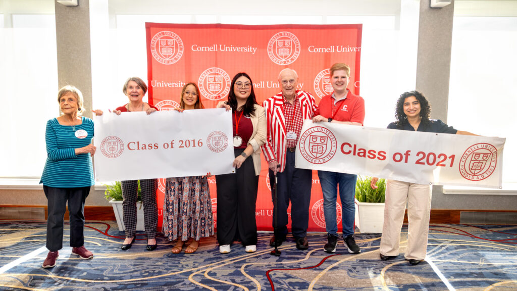 Alumni smile together for a photo with class banners at the “Spirit of ’31—Passing It Forward” ceremony in Statler Ballroom during Reunion 2026