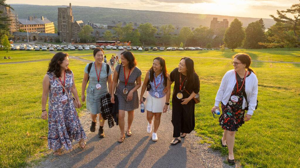 Six alumni walk up the Slope together as the sun sets during Reunion 2026