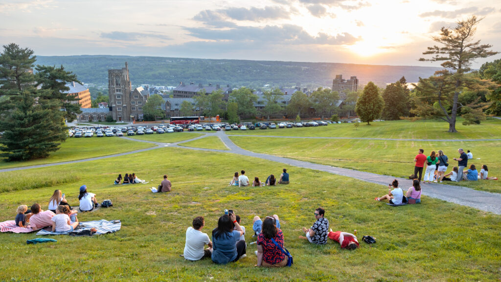 Small groups of alumni sit on the Slope together and watch the sunset at Reunion 2026