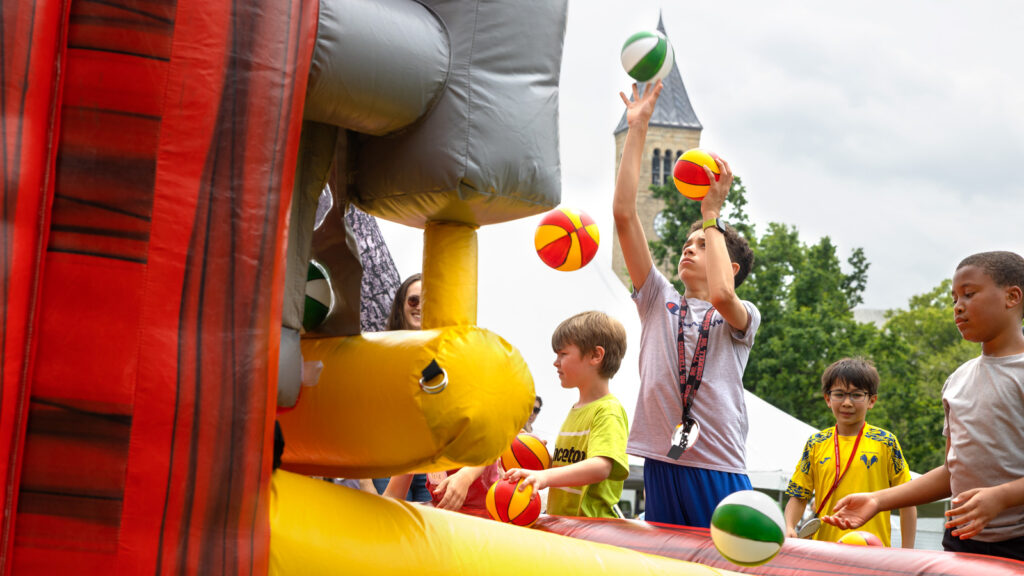 Children throw basketballs on an inflatable bounce house during an event on the Arts Quad at Reunion 2026