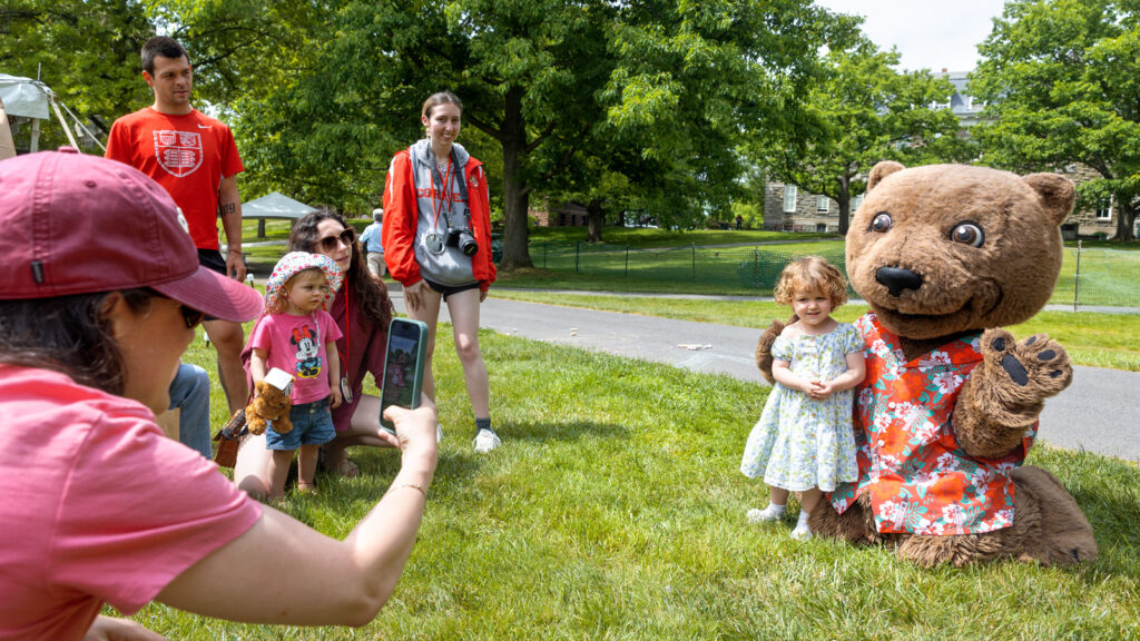 Touchdown and a young girl smile together for a photo during a Reunion 2026 event on the Arts Quad