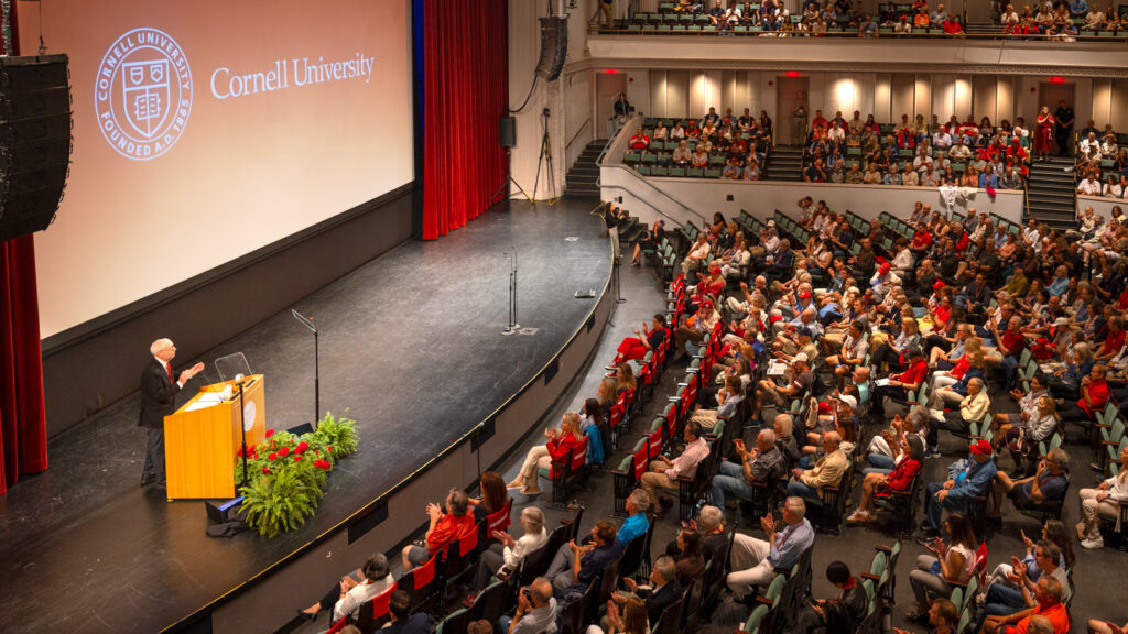 People sit in Bailey Hall as President Michael I. Kotlikoff speaks at the podium on stage during the State of the University Address during Reunion 2026