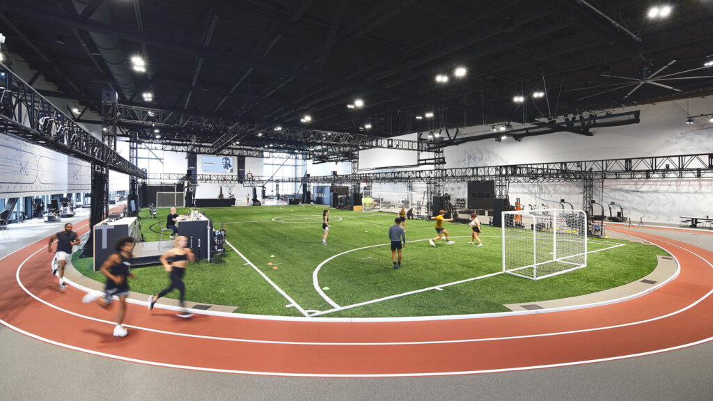 Athletes using the Nike Sport Research Lab, which features a turf field with soccer goals and a track around it