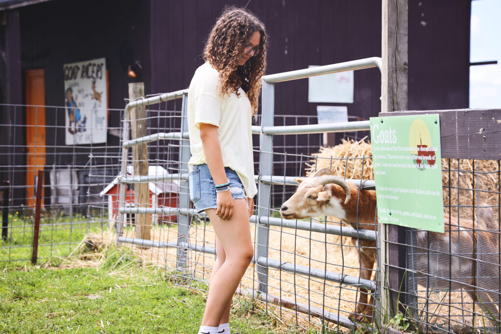 A girl stands next to goats at Becker Farms.