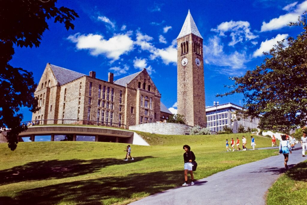 students walk down the south edge of Libe Slope with McGraw Tower and Uris and Olin libraries in the background, 1986