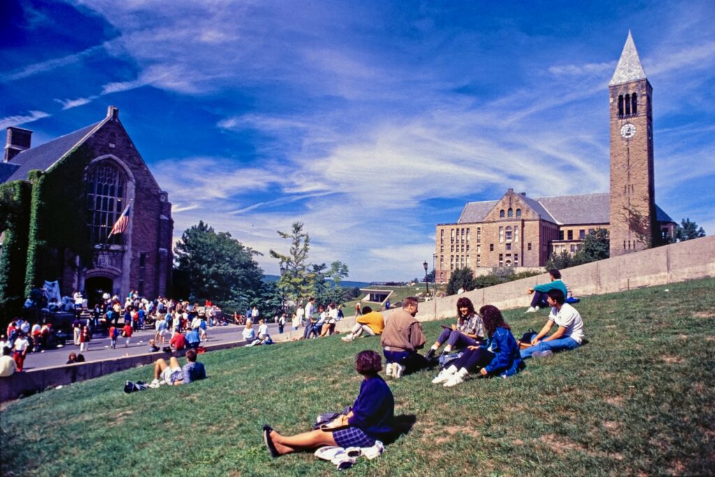students on the grass above the Cornell Store next to Ho Plaza in a vintage image