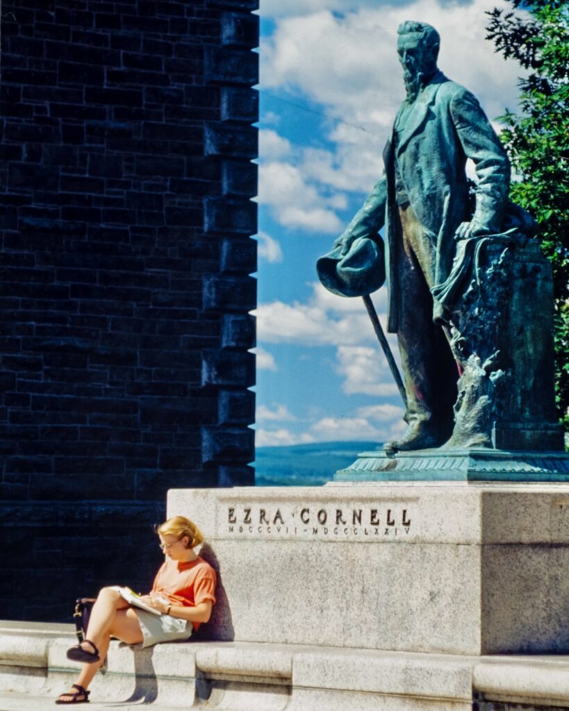 a student sits at the base of the Ezra Cornell statue in a vintage color photo from the 1990s