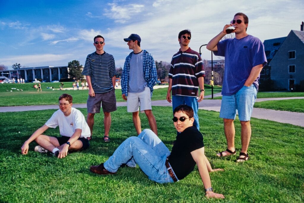 six student hang out on a North Campus lawn with Helen Newman Hall in the background in the 1990s