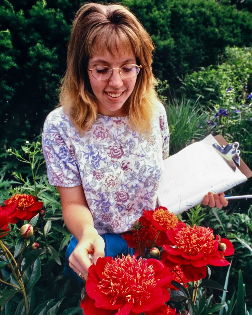 a student with a clipboard examines large red flowers in 1997