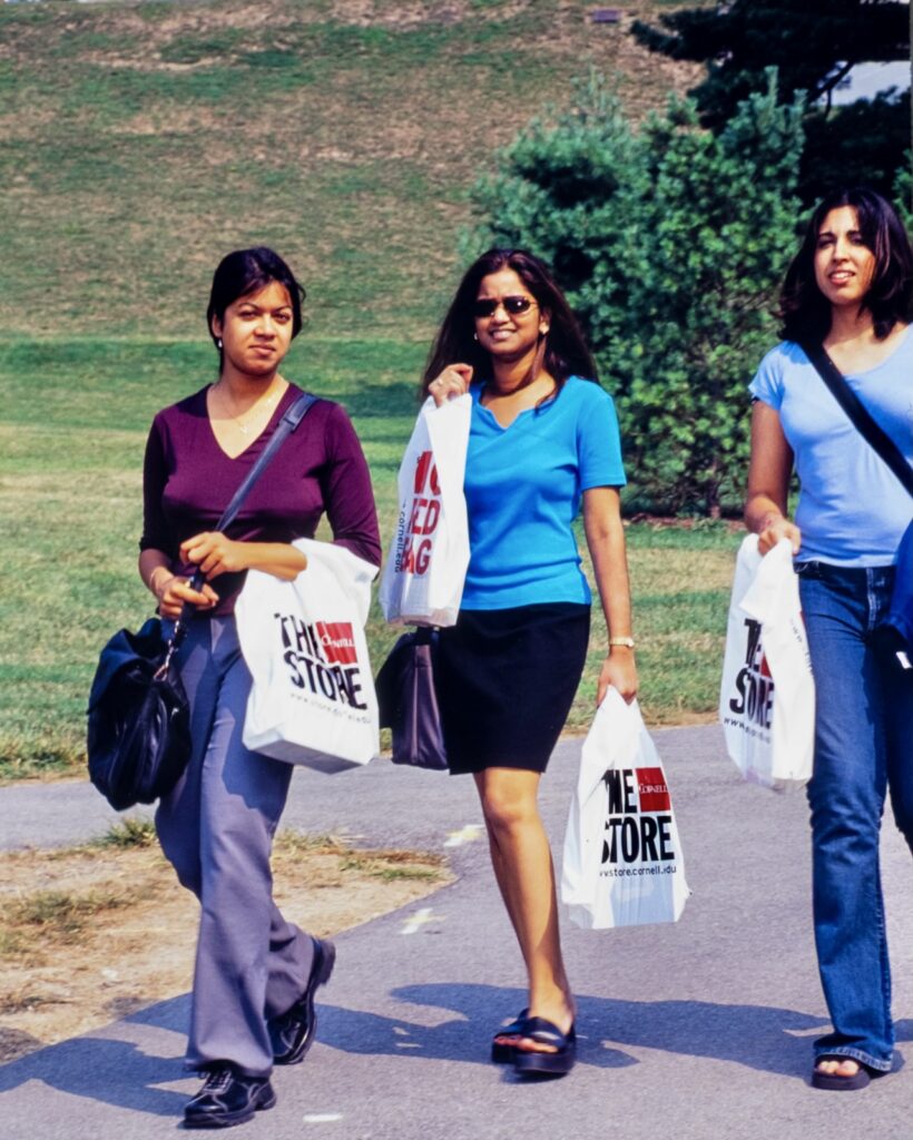 three people walk with Cornell Store bags on campus in 2001