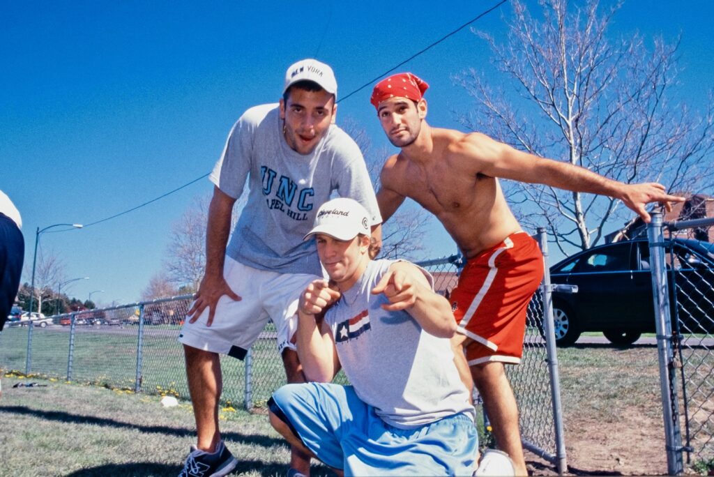 three male students pose outdoors near North Campus in 2002