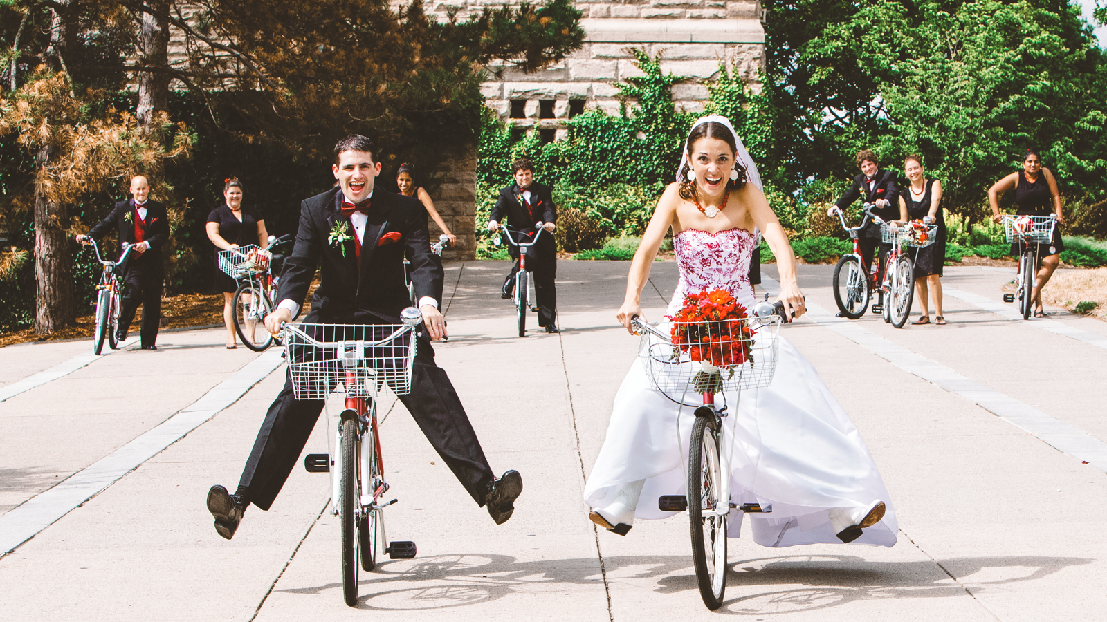 Gretchen Goldman ’06 & Tom Di Liberto ’06 ride bikes in their wedding attire outside McGraw Tower