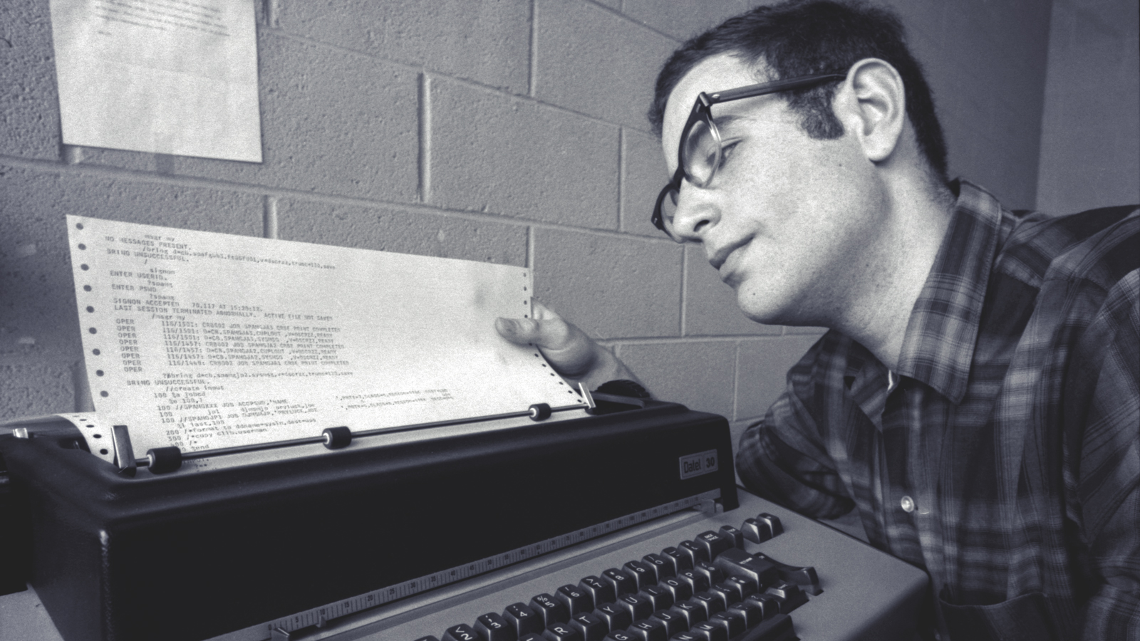 A male student looking at a printout on a midcentury typewriter