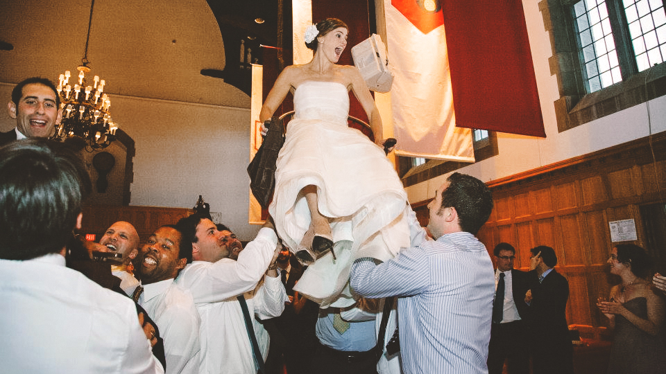 Jaime Wasserstrom Novikoff ’03 and Joshua Novikoff ’03 are carried on chairs in the WSH Memorial Room