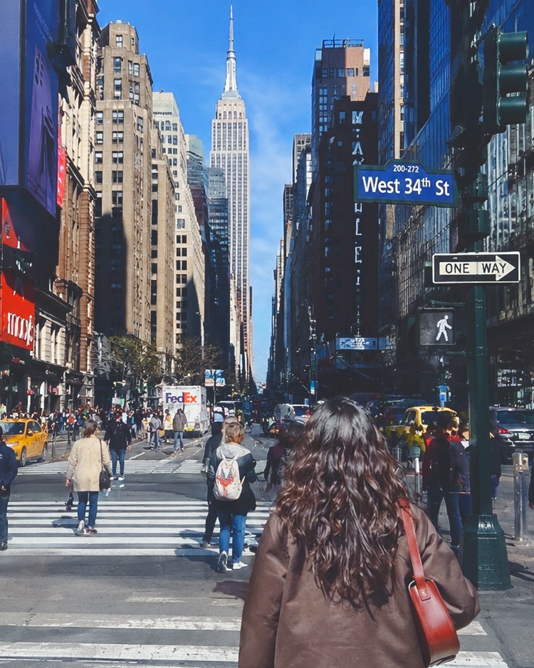 Serin Koh, seen from behind, walking on a Manhattan street with the Empire State Building in the background
