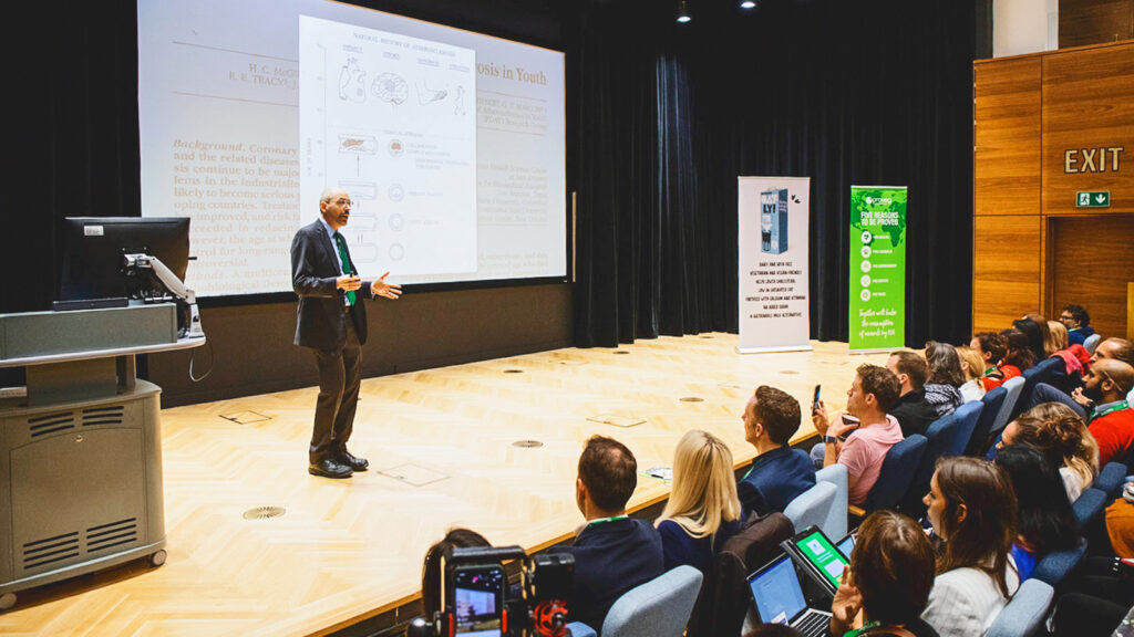 Dr. Michael Greger addresses an audience from a stage during a talk
