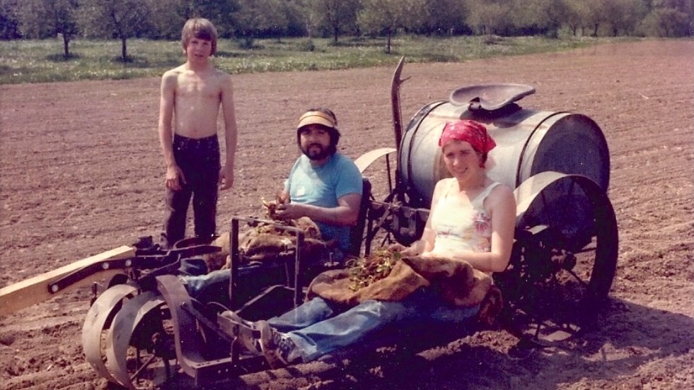 Melina and Oscar sitting on farm equipment with their son next to them.
