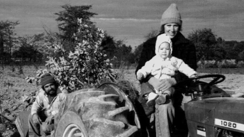 Melinda and Oscar as a young couple on a tractor with their baby.